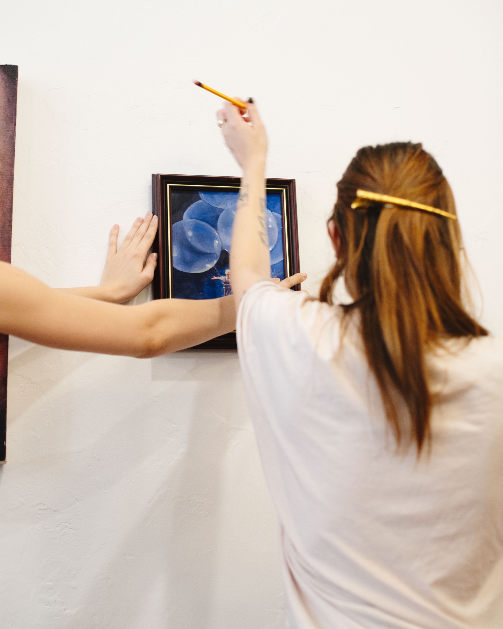 An artist hanging a framed blue artwork on the coffeehouse wall