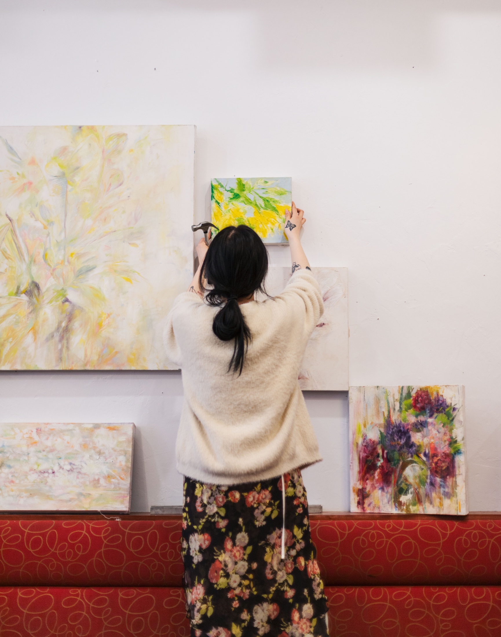 An artist installing a colourful painting among other works at Our Place