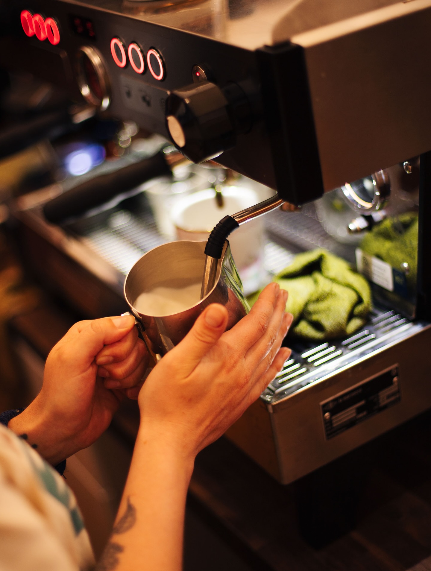 A barista steaming milk on the Our Place espresso machine