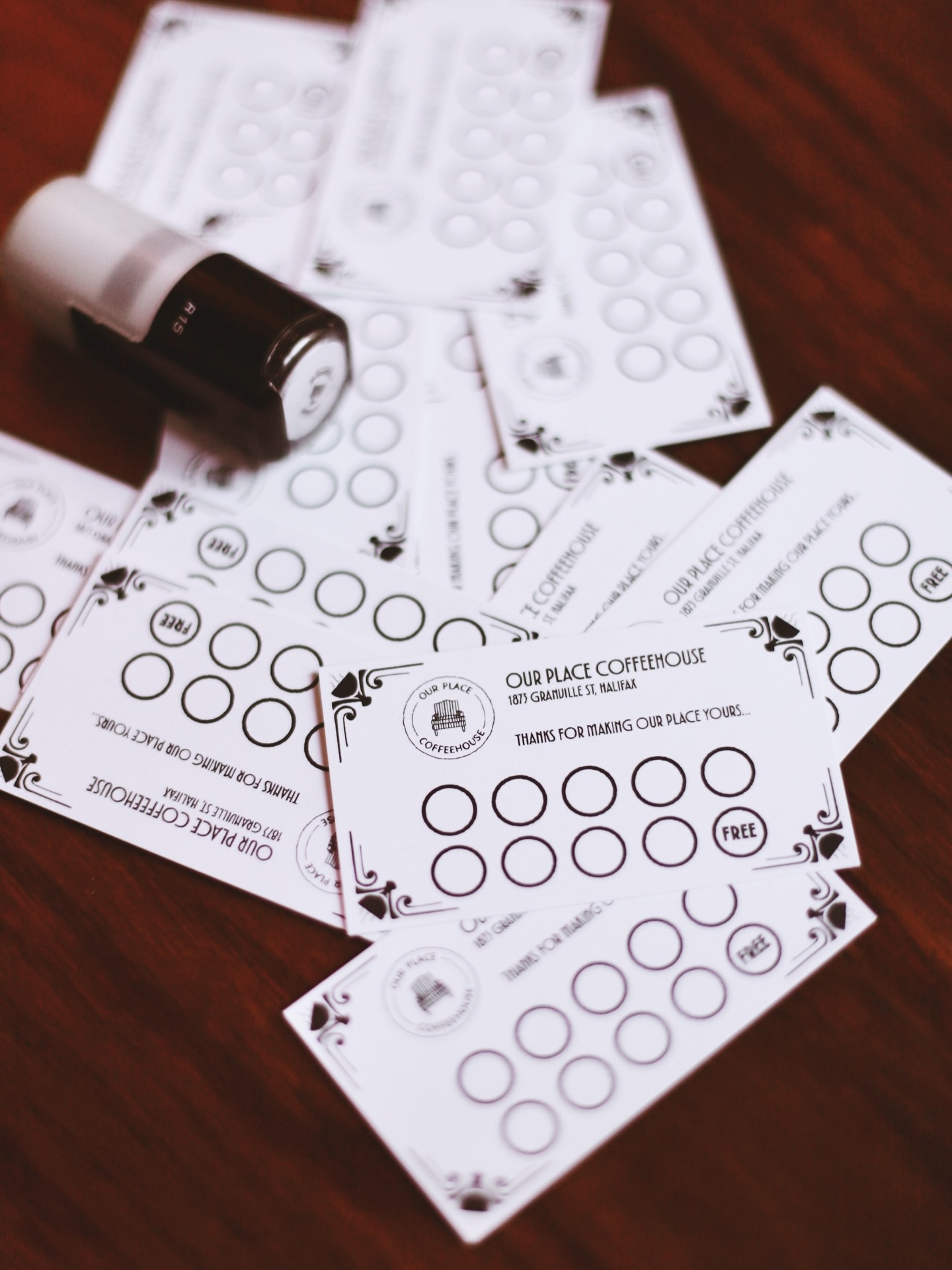 Our Place Coffeehouse loyalty stamp cards spread across a wooden table
