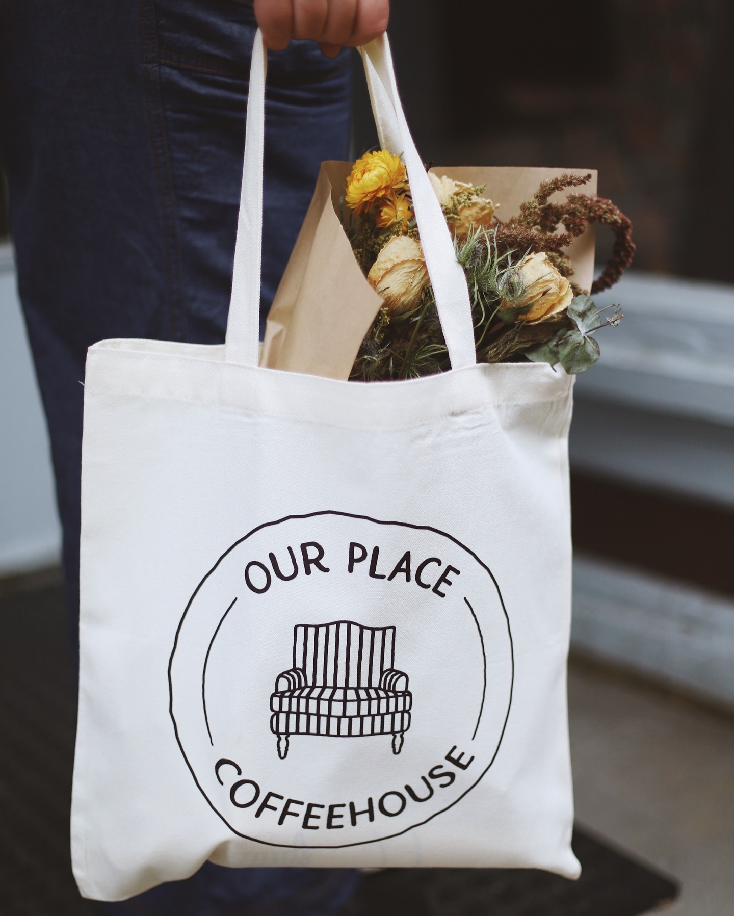 White Our Place Coffeehouse tote bag filled with flowers