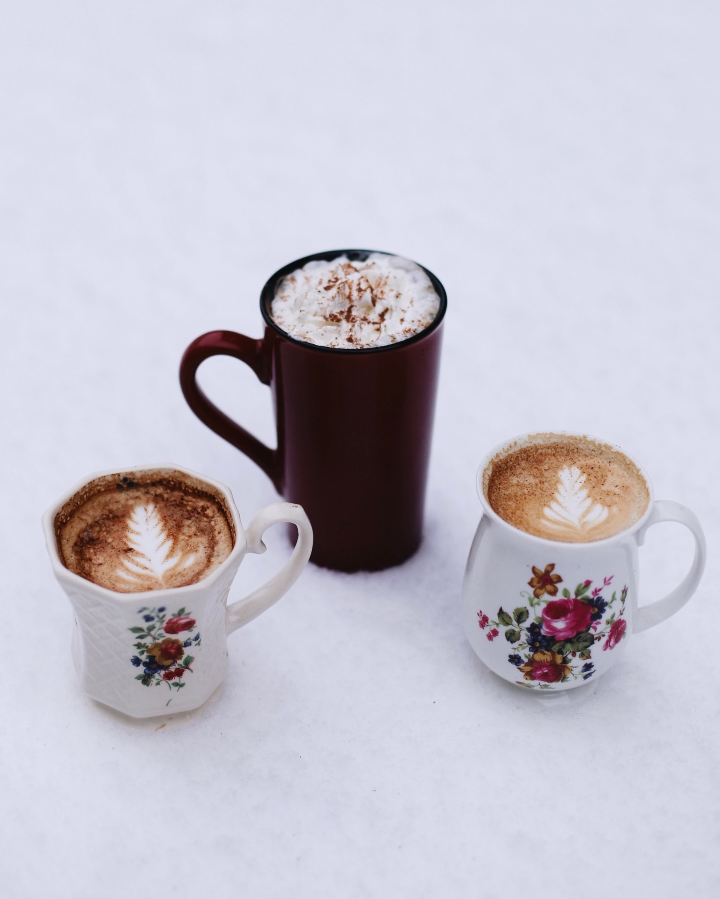 Three warm seasonal drinks served in vintage floral mugs